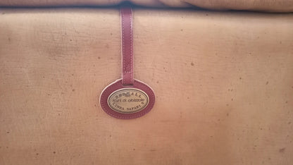 Etichetta ovale color borgogna appesa a un nastro per divano bogo in pelle e pelle scamosciata vintage
